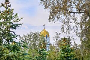 Christian cathedral with golden domes.Spring blooming green trees photo