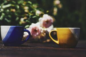 Tea time. Coffee break. Blue red yellow cups on wooden in blooming garden photo