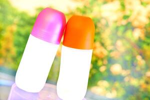 Orange pink top roll desodorant bottle for body care photo