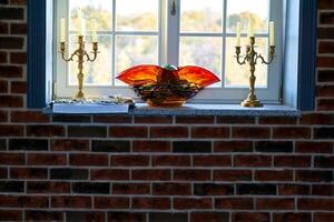 Window to the garden.Candlesticks,breakfast,an orange vase on a brick wall photo