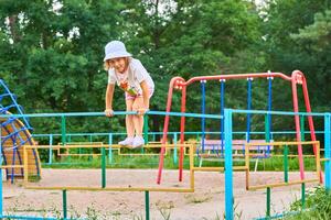Cute child d in a Panama hat, shorts and T shirt plays on the playground photo