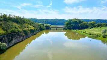 verano calma paz río fluido entre verde sierras. puente foto