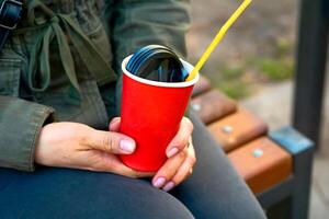 Women's hands hold an empty red paper plastic glass for drinks, coffee, tea photo