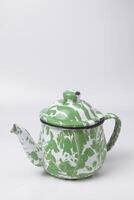 A portrait photo of a classic green and white teapot