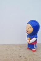 Side view photo of a toy Muslim girl wearing a blue headscarf