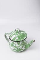 A portrait photo of a classic green and white teapot