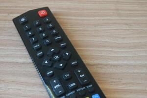 Black TV remote control on a wooden table photo