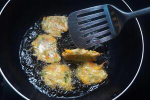 el proceso de mezcla crudo vegetales y trigo harina es frito en un fritura pan foto