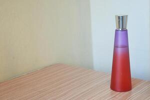 Perfume with red and purple glass bottles on a wooden table photo