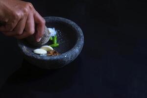 A girl hand is making chili sauce using a stone blender called Layah photo