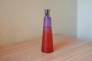 Perfume with red and purple glass bottles on a wooden table photo