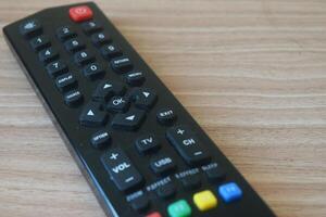 Black TV remote control on a wooden table photo