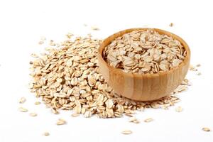 Raw organic oat flakes in wooden bowl on portion of oats isolated on white background. Photography for packaging photo