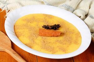 Curau, cream of corn sweet and dessert typical of the Brazilian cuisine, placed in ceramic bowl on wooden table. photo