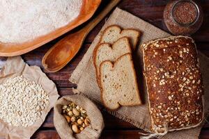 whole wheat bread with grains and seeds sliced on wooden table photo
