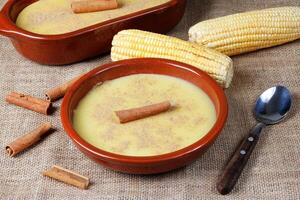 curau, crema de maíz dulce y postre típico de el brasileño cocina, metido en cerámico cuenco en de madera mesa. foto