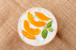 natural yogurt with peach in ceramic bowl on a table top view photo