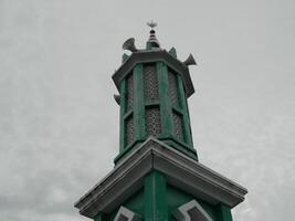 foto de el mezquita torre tomado desde el parte superior piso de un de muchos pisos edificio. el mezquita torre es usado como un marcador y además como un altoparlante