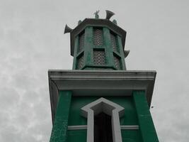 foto de el mezquita torre tomado desde el parte superior piso de un de muchos pisos edificio. el mezquita torre es usado como un marcador y además como un altoparlante