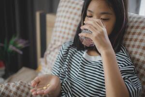 A girl is taking medicine and drinking water photo