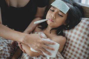 A woman is holding a child's forehead with a thermometer photo