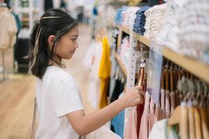 A young girl is shopping for clothes in a store photo