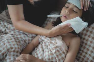 A woman is holding a child's forehead with a thermometer photo