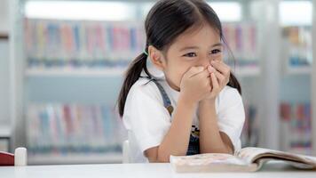 un joven niña es sentado a un mesa con un libro en frente de su foto