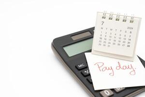 Hand writing text PAY DAY on July 2024 calendar with calculator in isolated background. Reminder concept of payment. copy space. photo