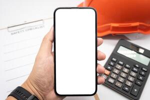 de ingeniero mano participación teléfono inteligente con blanco pantalla. Copiar espacio en Teléfono móvil pantalla. ingeniero trabajando en su teléfono inteligente foto