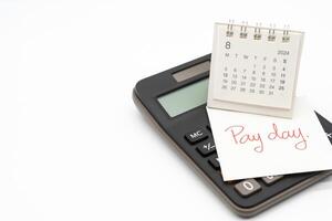 Hand writing text PAY DAY on August 2024 calendar with calculator in isolated background. Reminder concept of payment. copy space. photo