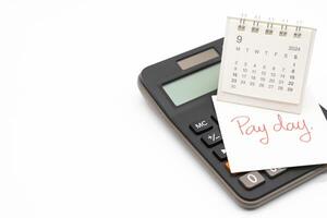 Hand writing text PAY DAY on September calendar with calculator in isolated background. Reminder concept of payment. photo