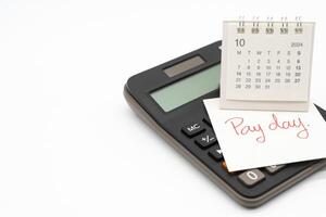 Hand writing text PAY DAY on October calendar with calculator in isolated background. Reminder concept of payment. copy space. photo