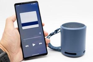 Hand using phone connecting portable speaker. Using bluetooth speaker with smart phone. photo