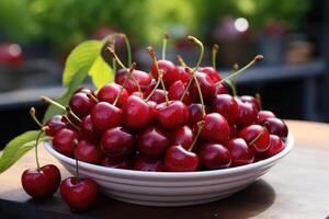 Fresh red cherries fruit in bowl on table in garden photo