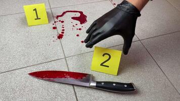 Criminology specialist places an evidence marker near knife of the murder weapon covered in blood video