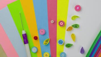 Twisted ribbons of colorful paper next to quilling tool, hobby with paper for developing fine motor skills video