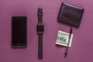 Business concept. Top view of dollars, watch, smartphone on color background photo