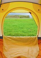 Kind from tent on lawn with green grass photo