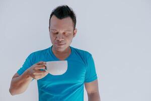 Happy Asian man feels refresh by drink and smell a cup of coffee. photo