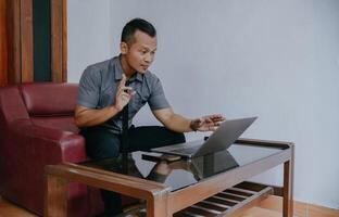 joven empresario trabajando en ordenador portátil. joven indonesio hombre concentrando en dando en línea educación clase conferencias foto