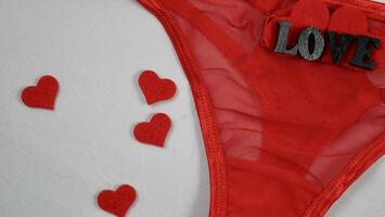 Valentine's Day Sexy Underwear Red Mesh Micro Panties Thong Hold Up String. Close-up in focus on white isolated background. with hearts photo