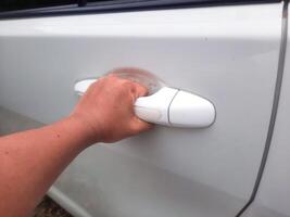 Man hand holding car door handle. Opening the vehicle door with left hand photo