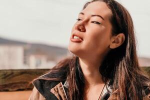 Happy young smiling woman with freckles outdoors portrait. Soft sunny colors. Outdoor close-up portrait of a young brunette woman and looking to the camera, posing against autumn nature background photo