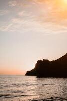A red burning sunset over the sea with rocky volcanic cliff. Abstract nature summer or spring ocean sea background. photo