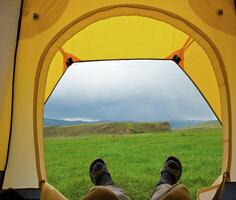 Man lying in tent with a view of mountain photo