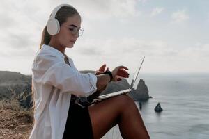 Woman sea laptop. Business woman, freelancer with laptop working over blue sea beach. Happy smiling girl relieves stress from work. Freelance, remote work on vacation, digital nomad, travel concept photo