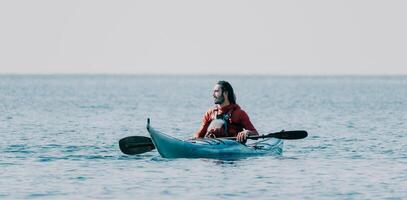 Man sea kayak. Happy free man in kayak on ocean, paddling with carbon paddle. Calm sea water and horizon in background. Active lifestyle at sea. Summer vacation. photo
