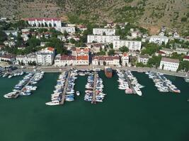 Aerial panoramic view of Balaklava landscape with boats and sea in marina bay. Crimea Sevastopol tourist attraction. Drone top view shot of port for luxury yachts, boats and sailboats. photo