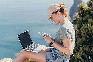 Woman sea laptop. Business woman, freelancer with laptop working over blue sea beach. Happy smiling girl relieves stress from work. Freelance, remote work on vacation, digital nomad, travel concept photo